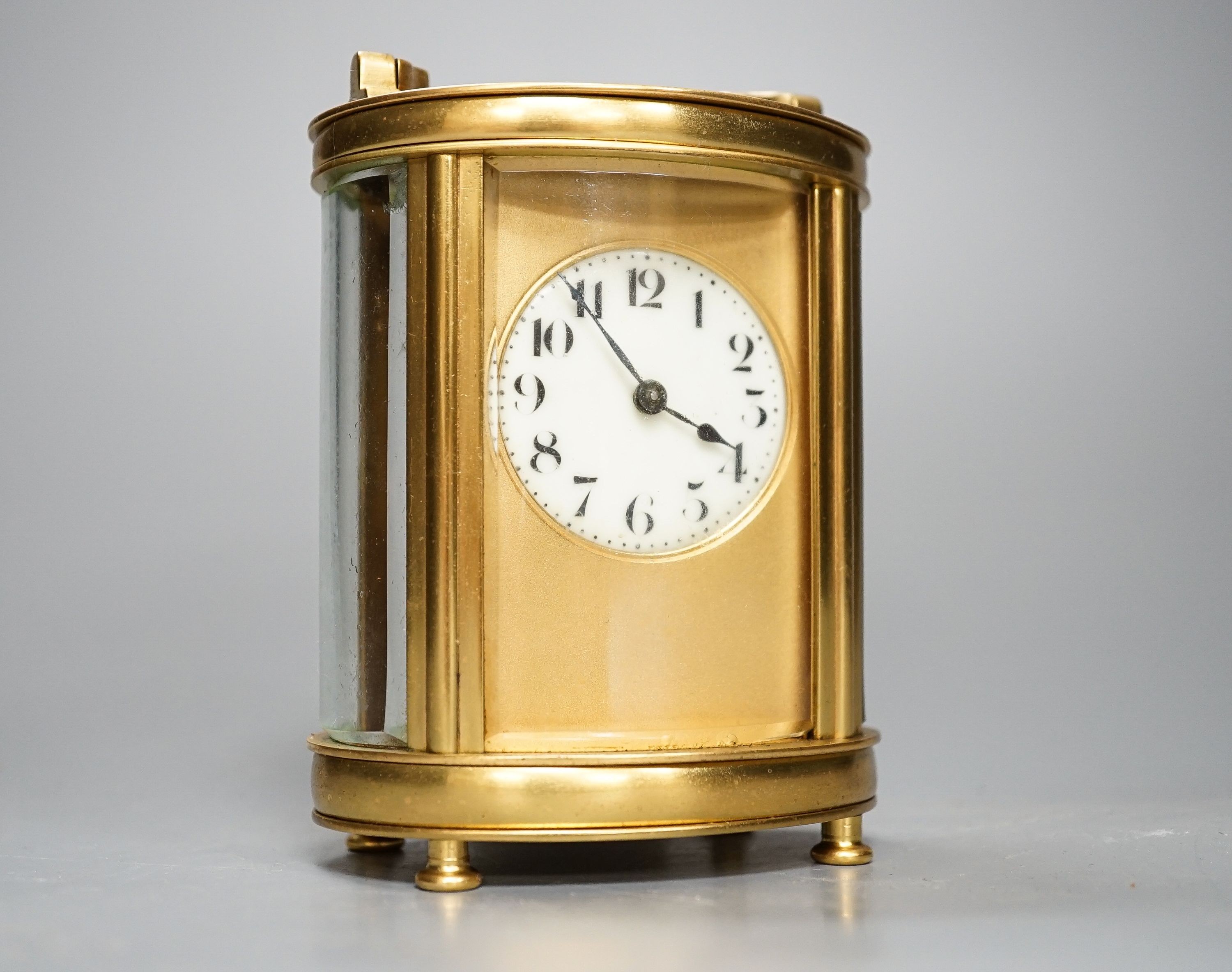 An oval brass cased carriage timepiece and associated carrying case.